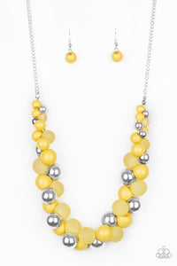 A bubbly collection of imperfect silver, opaque, and yellow beads are threaded along an invisible wire below the collar, creating a colorful cluster. Features an adjustable clasp closure.  Sold as one individual necklace. Includes one pair of matching earrings.