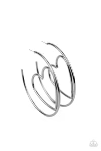 Shiny gunmetal wire delicately bends into an airy heart frame inside a classic gunmetal hoop, creating a flirtatious display. Earring attaches to a standard post fitting. Hoop measures approximately 2" in diameter. Sold as one pair of hoop earrings.