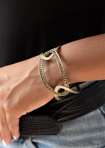 Two oval brass frames link with a matching brass frame encrusted in glittery aurum rhinestones, coalescing into an airy cuff around the wrist.  Sold as one individual bracelet.