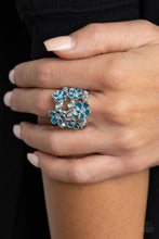 Load image into Gallery viewer, A whimsical collection of glassy white beads and shiny blue floral frames dot three shimmery silver bands across the finger, coalescing into a colorful centerpiece. Features a stretchy band for a flexible fit.  Sold as one individual ring.
