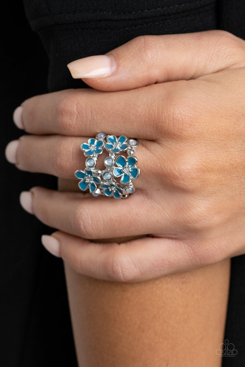 A whimsical collection of glassy white beads and shiny blue floral frames dot three shimmery silver bands across the finger, coalescing into a colorful centerpiece. Features a stretchy band for a flexible fit.  Sold as one individual ring.