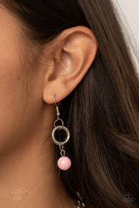 Pink bead hanging from a silver fish hook earring.