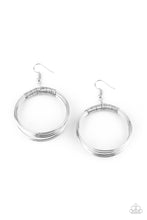 Load image into Gallery viewer, Dainty silver wire delicately wraps around layers of coiled silver wire, creating an edgy hoop. Earring attaches to a standard fishhook fitting. Sold as one pair of earrings.
