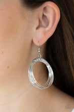 Load image into Gallery viewer, Dainty silver wire delicately wraps around layers of coiled silver wire, creating an edgy hoop. Earring attaches to a standard fishhook fitting.  Sold as one pair of earrings.
