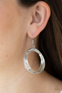 Dainty silver wire delicately wraps around layers of coiled silver wire, creating an edgy hoop. Earring attaches to a standard fishhook fitting.  Sold as one pair of earrings.