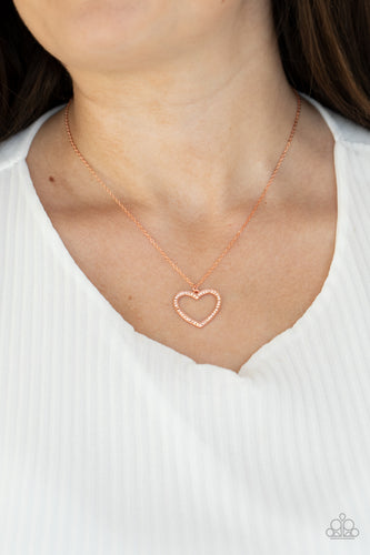 Encrusted in sparkly rhinestones, an airy shiny copper heart frame swings from a dainty shiny copper chain below the collar for a romantic look. Features an adjustable clasp closure.  Sold as one individual necklace. Includes one pair of matching earrings.