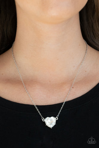 Cut into a flirtatious heart shape, a dramatically oversized white rhinestone pendant swings from the bottom of a dainty silver chain below the collar for a glamorous finish. Features an adjustable clasp closure.  Sold as one individual necklace. Includes one pair of matching earrings.