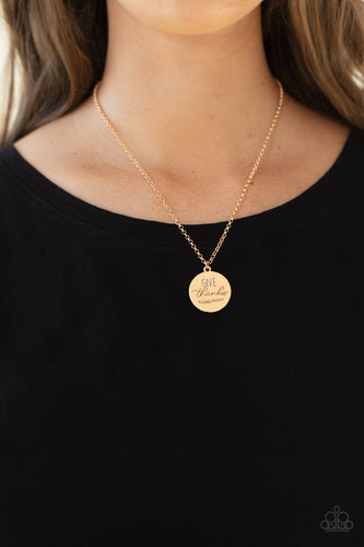Infused with feathery accents, a shiny gold disc is stamped in the phrase, 
