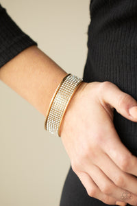 Row after row of white rhinestones are encrusted along the front of a thick gold cuff, creating a blinding statement piece around the wrist.  Sold as one individual bracelet.