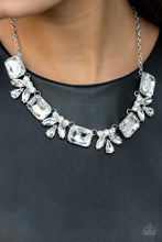Load image into Gallery viewer, An oversized collection of white emerald cut gems and regally cut clusters of rhinestones delicately link below the collar, creating a dramatically sparkly fringe. Features an adjustable clasp closure.  Sold as one individual necklace. Includes one pair of matching earrings. 

