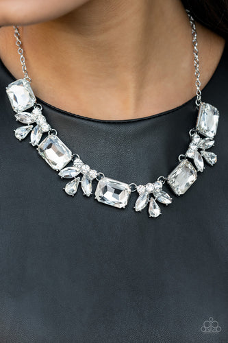 An oversized collection of white emerald cut gems and regally cut clusters of rhinestones delicately link below the collar, creating a dramatically sparkly fringe. Features an adjustable clasp closure.  Sold as one individual necklace. Includes one pair of matching earrings. 