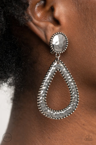 Bordered in antiqued silver studs, a hammered disc attaches to a hammered teardrop, creating a rustic lure. Earring attaches to a standard clip-on fitting.  Sold as one pair of clip-on earrings.