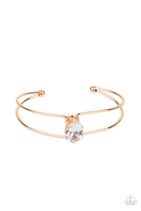 A dramatically oversized white rhinestone is fitted in place atop the center of a gold wire cuff, creating a jaw-dropping display around the wrist.  Sold as one individual bracelet.