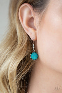 Turquoise stone hanging from a fish hook earring.