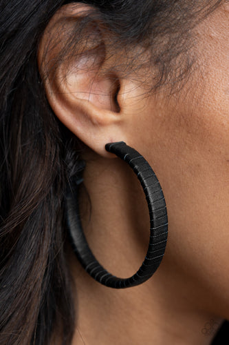A black leather lace wraps around a thick silver hoop, creating an edgy display. Earring attaches to a standard post fitting. Hoop measures approximately 2 1/2