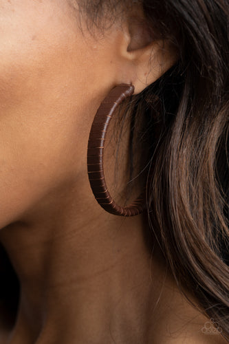 A rustic brown leather lace wraps around a thick silver hoop, creating an edgy display. Earring attaches to a standard post fitting. Hoop measures approximately 2 1/2