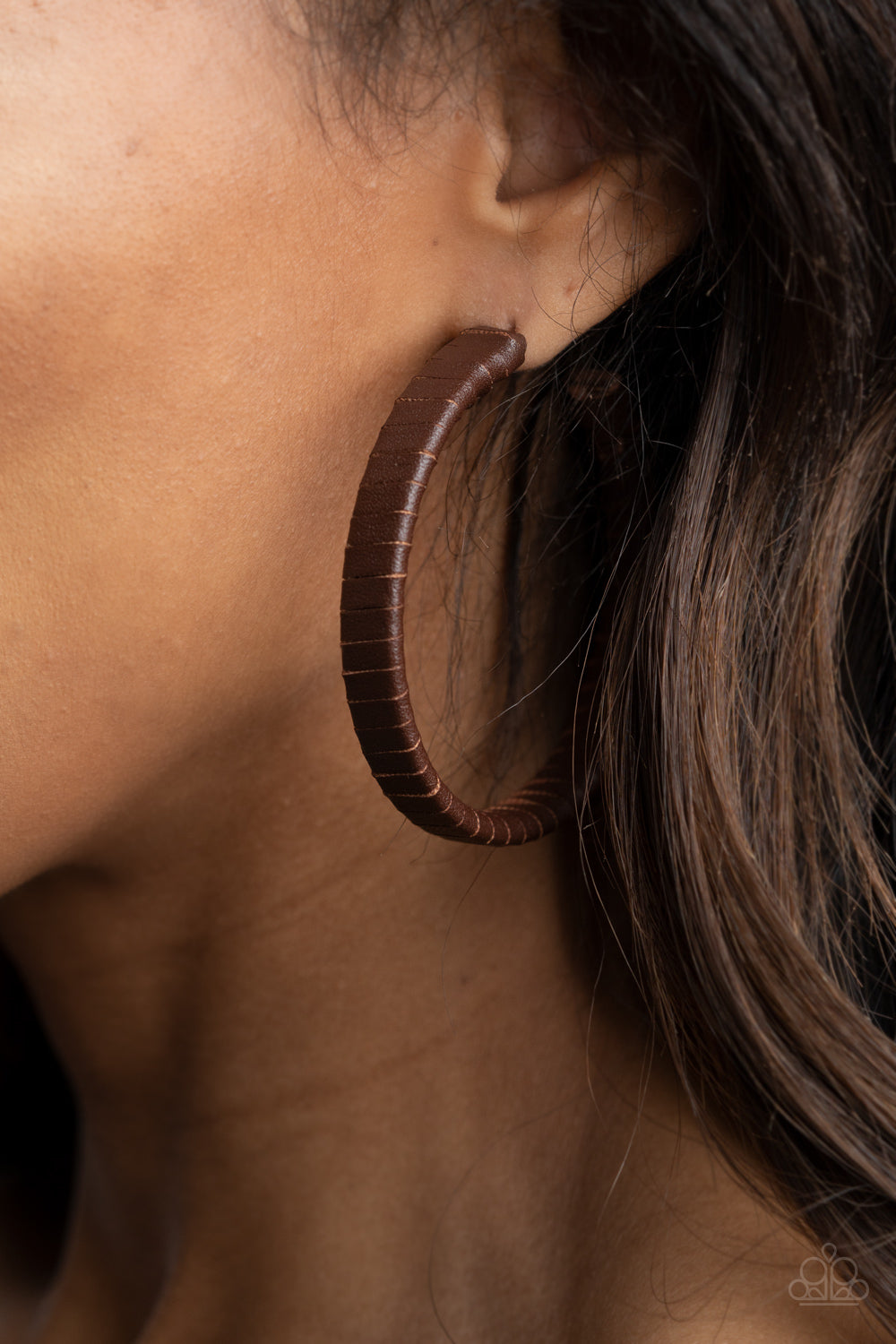A rustic brown leather lace wraps around a thick silver hoop, creating an edgy display. Earring attaches to a standard post fitting. Hoop measures approximately 2 1/2