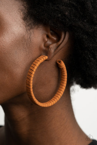 Tan suede cording wraps around an oversized hoop, creating an earthy pop of color. Earring attaches to a standard post fitting. Hoop measures approximately 2 1/4