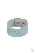 Load image into Gallery viewer, The front of a Cerulean leather band is stamped in a decorative butterfly and flower pattern, creating a whimsical display around the wrist. Features an adjustable snap closure.  Sold as one individual bracelet.
