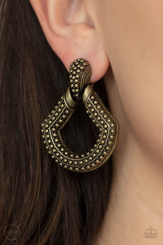 Dotted in rows of studded detail, an oversized brass buckle-like frame adorns the ear for a rustic fashion. Earring attaches to a standard clip-on fitting.  Sold as one pair of clip-on earrings.