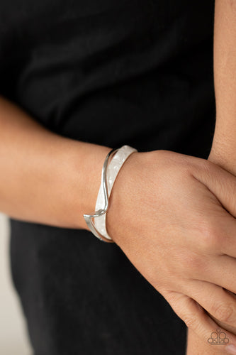 A flat silver bar delicately curls across a dainty white shell-like acrylic cuff, creating a whimsical centerpiece around the wrist.  Sold as one individual bracelet.
