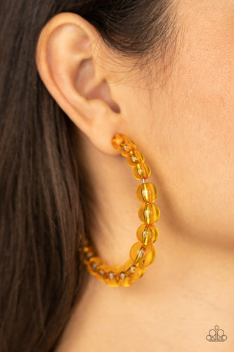 Gradually increasing in size at the center, a glassy collection of Marigold beads are threaded along an oversized hoop for a bubbly effect. Earring attaches to a stand post fitting. Hoop measures approximately 2 1/2