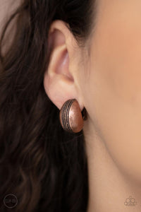The center of a round copper frame is embossed in textured columns, accentuating the frame's dainty curve. Earring attaches to a standard clip-on fitting.  Sold as one pair of clip-on earrings.