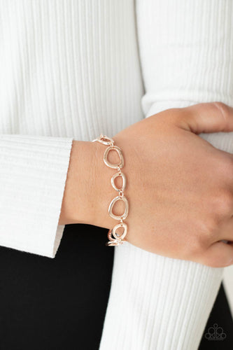 An array of irregular shaped rose gold rings link together and make their way around the wrist for a simple yet stylish avant-garde fashion. Features an adjustable clasp closure.