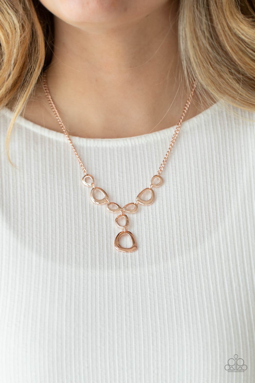 Irregular shaped rose gold rings connect to a rose gold chain as they make their way across the collar. Two rings dangle from the center for a stylish avant-garde fashion. Features an adjustable clasp closure. Includes one pair of matching earrings.