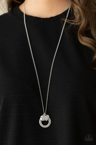 Dotted with a sparkly pink rhinestone, a dainty silver heart joins a silver ring stamped in the biblical passage, 