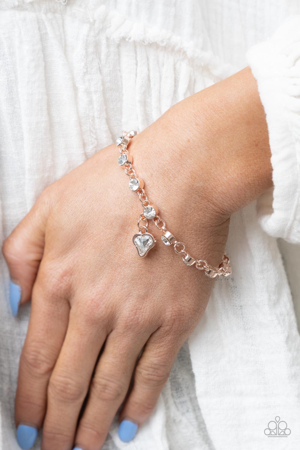 Brilliant white rhinestones in rose gold settings are linked together and accented with a charming white rhinestone heart that dangles sweetly from the wrist. Features an adjustable clasp closure.  Sold as one individual bracelet.
