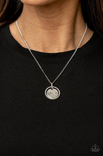 Infused with a silver ring of glassy white rhinestones, a glistening silver disc is dotted with a dainty white rhinestone and stamped in the word, 