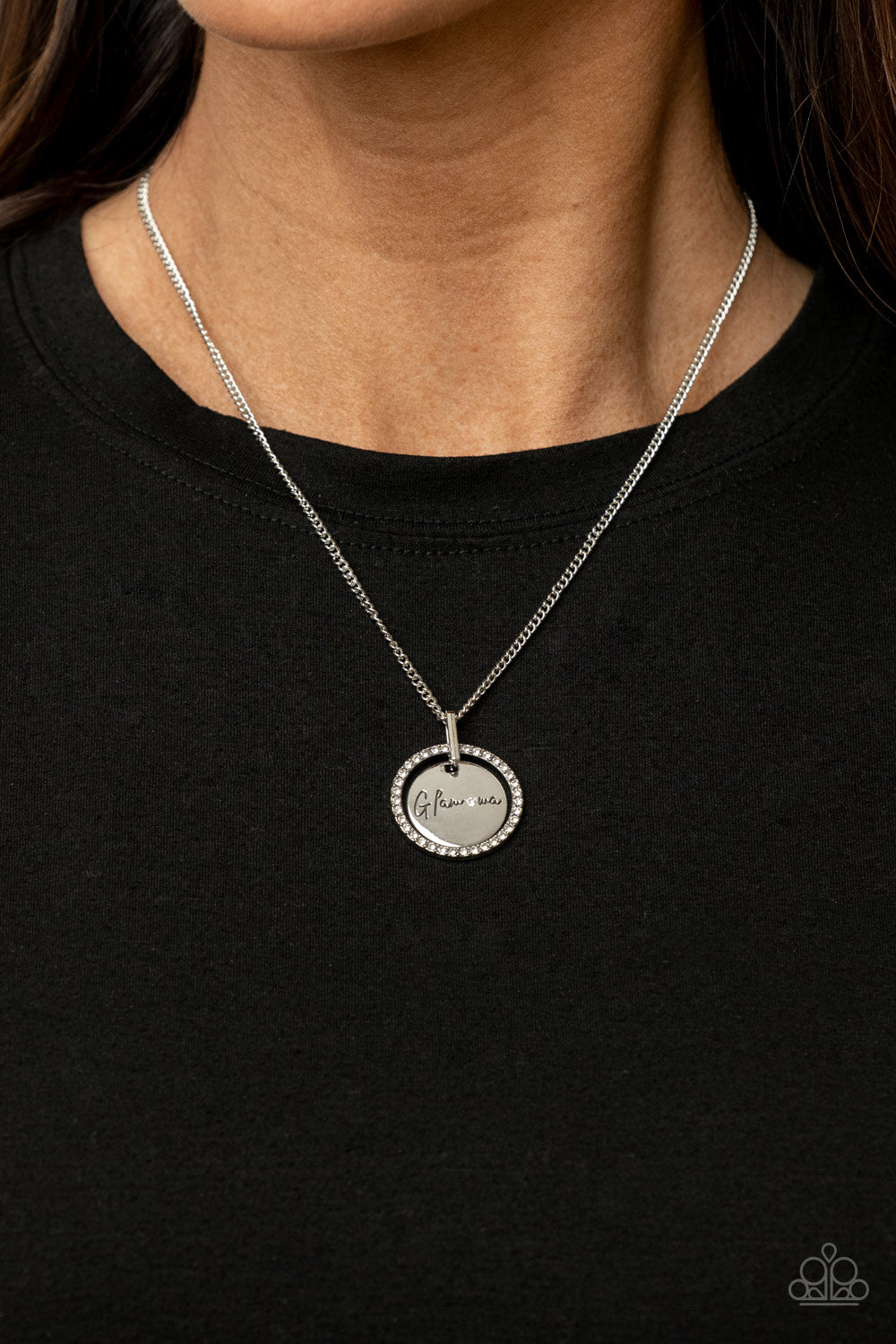 Infused with a silver ring of glassy white rhinestones, a glistening silver disc is dotted with a dainty white rhinestone and stamped in the word, 