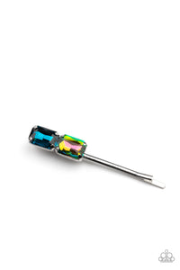 Featuring elegant emerald style cuts, an oversized pair of blue and oil spill rhinestones adorn the end of a classic silver bobby pin.  Sold as one individual bobby pin.