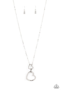 A silver heart engraved with the word "Grandma," dangles from two smaller hearts at the bottom of a lengthened silver chain. The first heart is accented with sparkly white rhinestones creating an affectionately sentimental pendant. Features an adjustable clasp closure.  Sold as one individual necklace. Includes one pair of matching earrings.