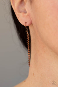Copper chain hanging from a fish hook earring.