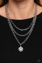 Load image into Gallery viewer, A trio of silver paperclip, classic, and oval link chains coalesces down the neckline for a monochromatic masterpiece. Strung on the lowermost oval link chain, a silver smiley face pendant, with a star mimicking a wink for one of its eyes, stands out and reflects light in every direction for a statement finish. Features an adjustable clasp closure.  Sold as one individual necklace. Includes one pair of matching earrings.
