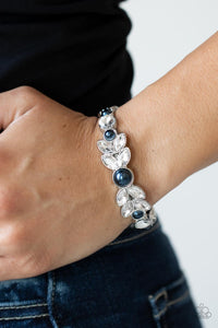 Dotted with bubbly blue pearls, an oversized collection of round and marquise style white rhinestones boldly coalesce into a sparkly centerpiece that is flanked by stacks of leafy silver frames that gracefully curve into a decorative cuff.  Sold as one individual bracelet.