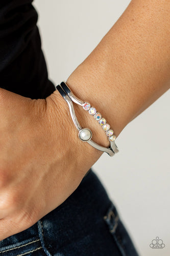 A row of iridescent rhinestones and a solitaire white pearl adorn the layered center of a classic silver cuff, creating a timeless piece around the wrist.  Sold as one individual bracelet.