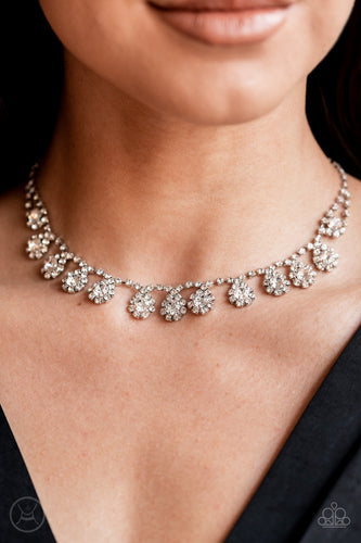 A dainty strand of glittery white rhinestones encircle solitaire white rhinestones around the neck, creating a glitzy fringe. Features an adjustable clasp closure.  Sold as one individual choker necklace. Includes one pair of matching earrings.