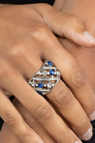 Bubbly rows of dainty opaque rhinestones, glassy blue cat's eye stones, and classic white rhinestones alternate with classic bands of dainty white rhinestones across the finger, coalescing into an effervescently elegant centerpiece. Features a stretchy band for a flexible fit.  Sold as one individual ring.