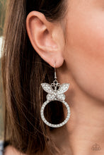 Load image into Gallery viewer, A white rhinestone encrusted silver butterfly flutters atop a silver ring dotted in matching white rhinestones, resulting in a dazzling statement piece. Earring attaches to a standard fishhook fitting.  Sold as one pair of earrings.
