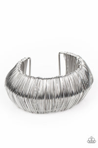 Layer after layer of glistening silver wire wraps around an oversized silver cuff. The center of the wire wrap comes to a peak, adding edge to the intense industrial display.  Sold as one individual bracelet.