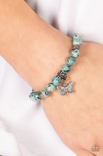 Infused with a silver butterfly charm, textured silver accents and black speckled blue stone beads are threaded along stretchy bands around the wrist for a whimsical look.  Sold as one individual bracelet.