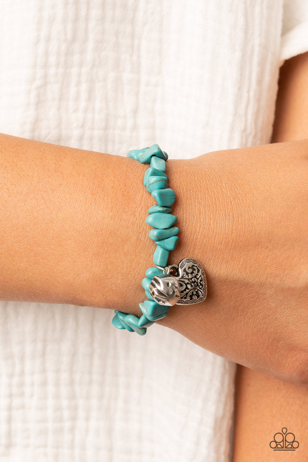 Infused with a hammered silver bead and a decorative silver heart charm, an earthy collection of turquoise pebbles are threaded along a stretchy band around the wrist for a whimsical fashion.  Sold as one individual bracelet.