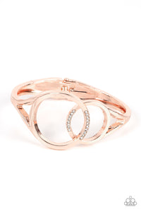 Encrusted in sections of glassy white rhinestones, two oversized rose gold rings delicately overlap across the center of the wrist, resulting in a timeless bangle-like bracelet around the wrist. Features a hinged closure.  Sold as one individual bracelet.