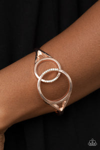 Encrusted in sections of glassy white rhinestones, two oversized rose gold rings delicately overlap across the center of the wrist, resulting in a timeless bangle-like bracelet around the wrist. Features a hinged closure.  Sold as one individual bracelet.