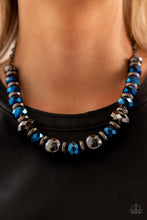 Load image into Gallery viewer, A dramatic assortment of oversized gunmetal beads, textured gunmetal rings, and faceted metallic blue gems delicately glides along an invisible wire below the collar, resulting in a stellar sparkle. Features an adjustable clasp closure. Includes one pair of matching earrings.
