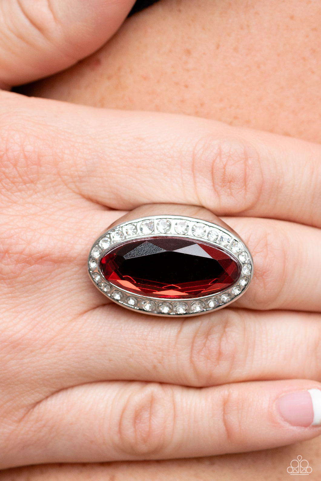 Bordered by a glitzy ring of white rhinestones, an oblong red gem embellishes the center of a dramatically oversized silver frame for a blinding finish. Features a stretchy band for a flexible fit.  Sold as one individual ring.