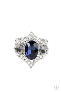 An oversized blue oval gem is flanked by a pair of smoky teardrop rhinestones atop a white rhinestone dotted frame, resulting in a dramatic dazzle atop the finger. Features a stretchy band for a flexible fit.  Sold as one individual ring.